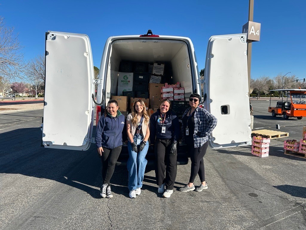 AVPH volunteers beside a van loaded with supply boxes.